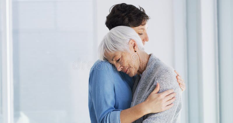 Triste conforto e donna che abbracciano madre anziana in casa di riposo per dolore o perdita. Amore emotivo e donna fotografie stock