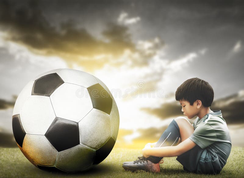 Um garoto segurando a velha bola de futebol antes de começar um jogo de  futebol