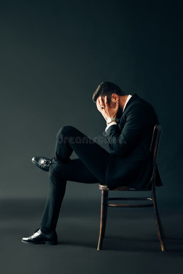 Triste Homem Infeliz De Fato Preto Sentado Na Cadeira E Na Face Fechada Por  Duas Mãos Imagem de Stock - Imagem de fechado, assustado: 163081299