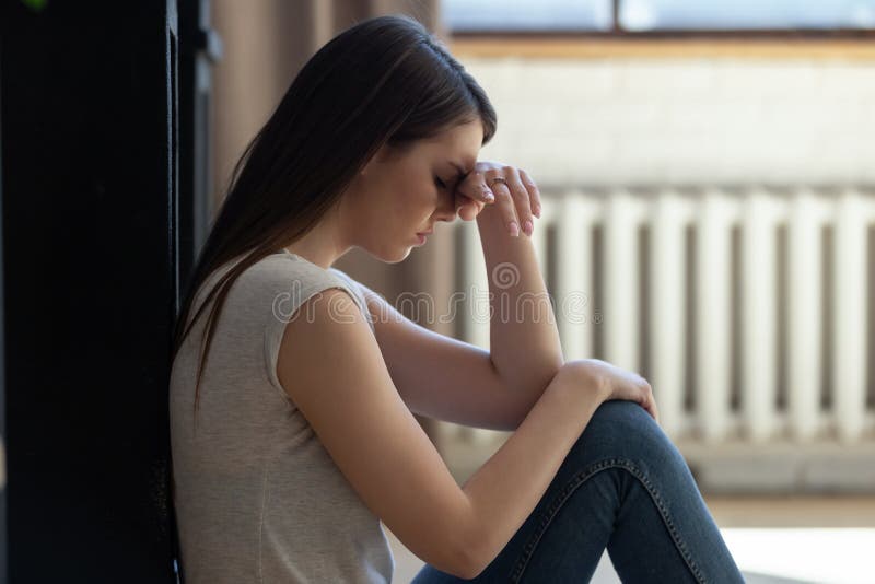 Menina triste sentada sozinha no chão