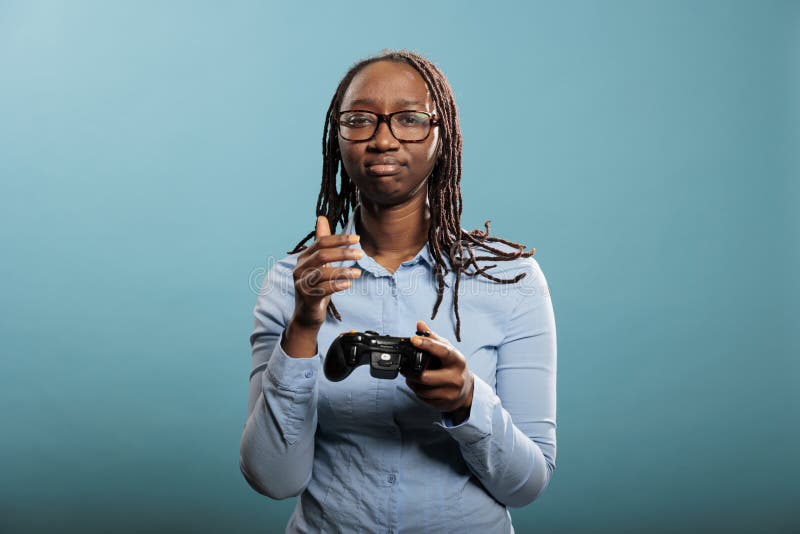 Triste joven mujer adulta con controlador de consola de juegos moderno de fondo azul. fotos de archivo libres de regalías