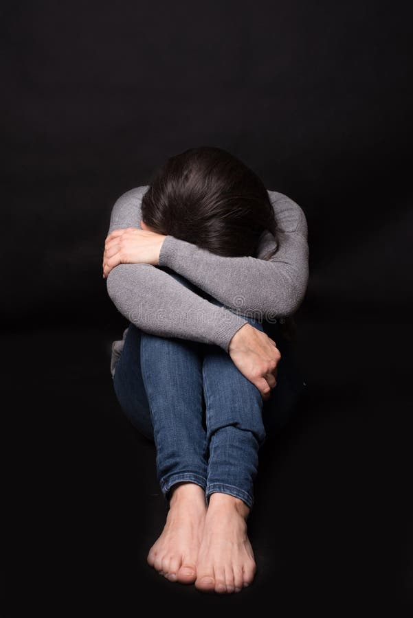 Triste Mulher Sentada Em Um Fundo Negro Foto de Stock - Imagem de