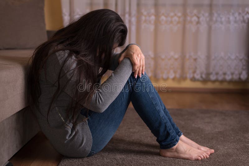 Triste Mulher Sentada Em Um Fundo Negro Foto de Stock - Imagem de