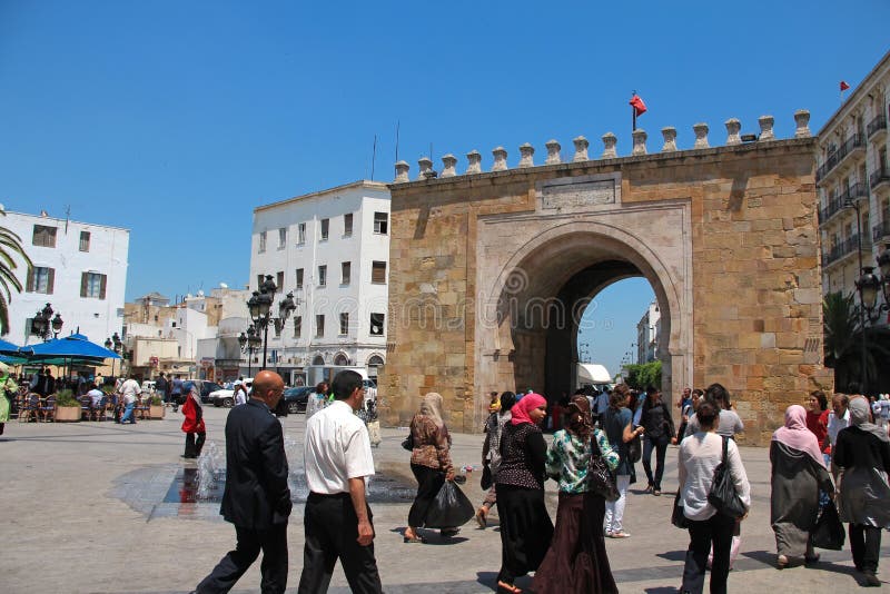 TUNISIA, TUNIS, JUNE 30, 2010: Downtown in Tunis, Tunisia. People near triumphal arch. The triumphal arch at the end of the boulevard at the entrance to the medina. TUNISIA, TUNIS, JUNE 30, 2010: Downtown in Tunis, Tunisia. People near triumphal arch. The triumphal arch at the end of the boulevard at the entrance to the medina.