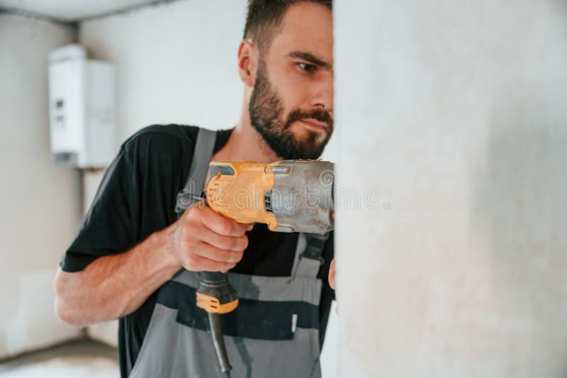 Trivellazione nel muro. l'uomo sta riparando nell'appartamento fotografie stock