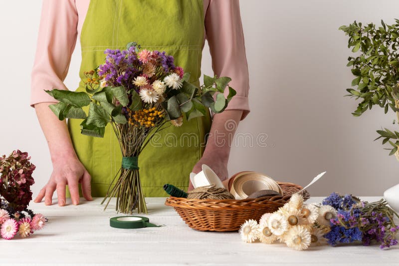 Trockenblumen. Blumenweibchen, die getrocknete Blumen zu einem schönen Bouquet arrangieren. nachhaltige Blüte. stockfotografie
