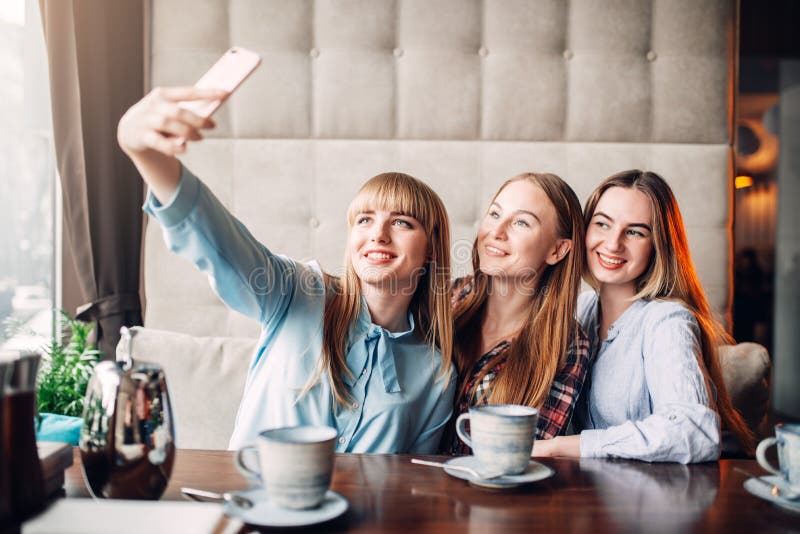 Trois amies fait le selfie sur l'appareil-photo en café photographie stock libre de droits Trois amies fait le selfie sur l'appareil-photo en café photographie stock libre de droits