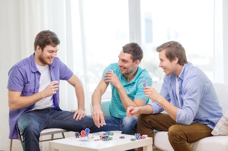 Trois amis masculins heureux jouant le tisonnier à la maison photo stock Trois amis masculins heureux jouant le tisonnier à la maison photo stock
