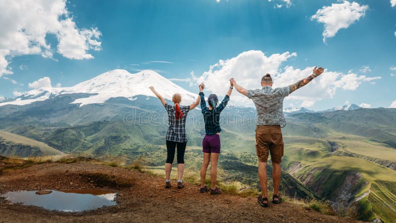 Trois amis ont joint des mains et ont soulevé leurs mains, appréciant la vue des montagnes pendant l'été Vacances d'été C extérie photos stock Trois amis ont joint des mains et ont soulevé leurs mains, appréciant la vue des montagnes pendant l'été Vacances d'été C extérie photos stock