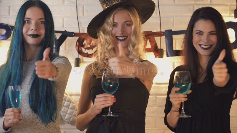 Trois belles femmes montrant des pouces lèvent le geste, ayant l'amusement la veille de Halloween banque de vidéos