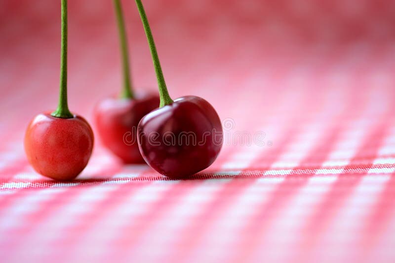 Trois cerises rouges sur une table photographie stock Trois cerises rouges sur une table photographie stock