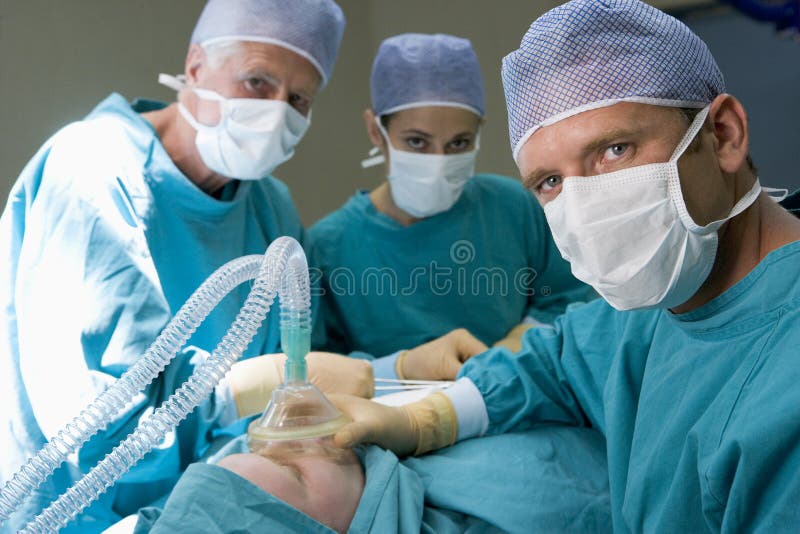Trois chirurgiens fonctionnant sur un patient images libres de droits Trois chirurgiens fonctionnant sur un patient images libres de droits
