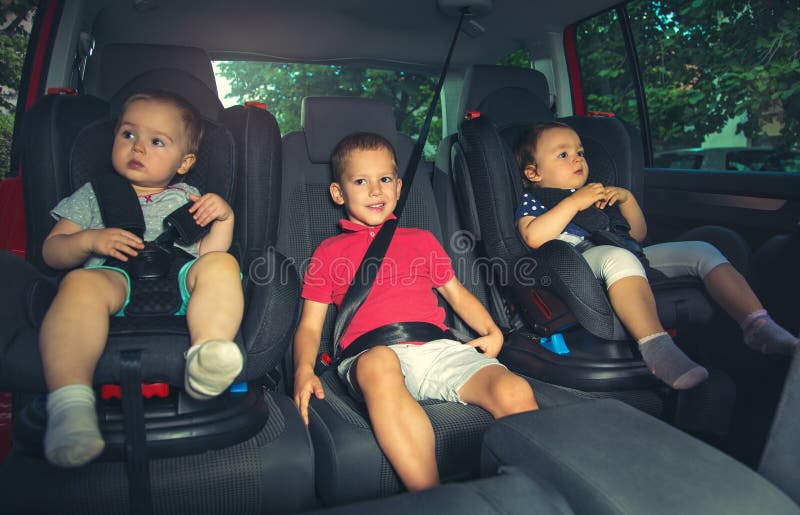 Trois enfants dans le siège de sécurité de voiture photos stock Trois enfants dans le siège de sécurité de voiture photos stock