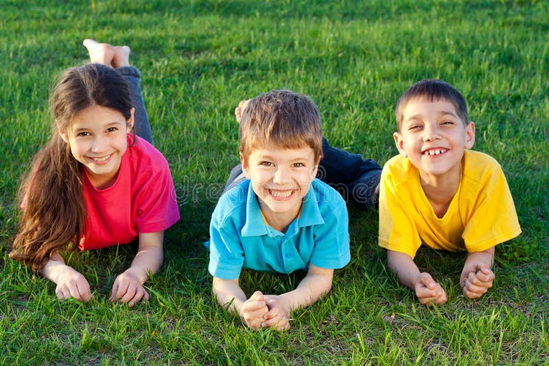 Trois enfants de sourire sur le pré photographie stock libre de droits Trois enfants de sourire sur le pré photographie stock libre de droits