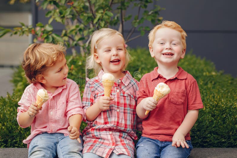 Trois enfants en bas âge drôles adorables mignons caucasiens blancs d'enfants s'asseyant ensemble partageant la glace photos stock Trois enfants en bas âge drôles adorables mignons caucasiens blancs d'enfants s'asseyant ensemble partageant la glace photos stock