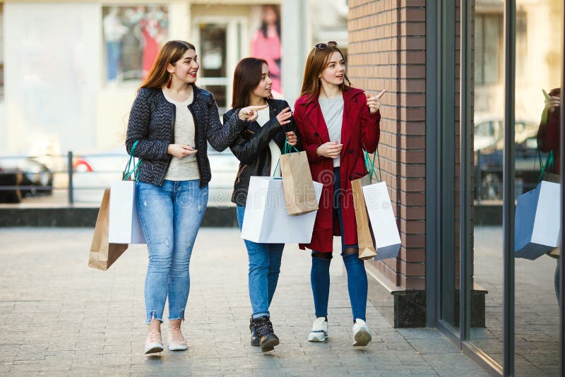 Trois femmes avec le point de paniers à la fenêtre de boutique photo stock Trois femmes avec le point de paniers à la fenêtre de boutique photo stock
