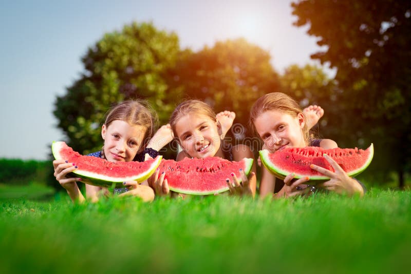 Trois filles mignonnes mangeant la pastèque photographie stock Trois filles mignonnes mangeant la pastèque photographie stock