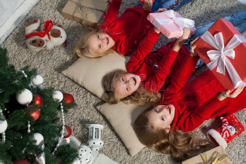 Trois filles se trouvent près d'un arbre de Noël avec l'hiver de vacances de nouvelle année de cadeaux image stock Trois filles se trouvent près d'un arbre de Noël avec l'hiver de vacances de nouvelle année de cadeaux image stock