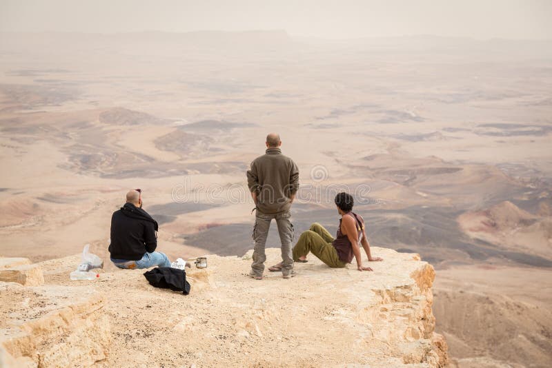 Trois hommes observant l'horizon au bord de la falaise de cratère de Ramon au désert du Néguev, Israël image libre de droits Trois hommes observant l'horizon au bord de la falaise de cratère de Ramon au désert du Néguev, Israël image libre de droits