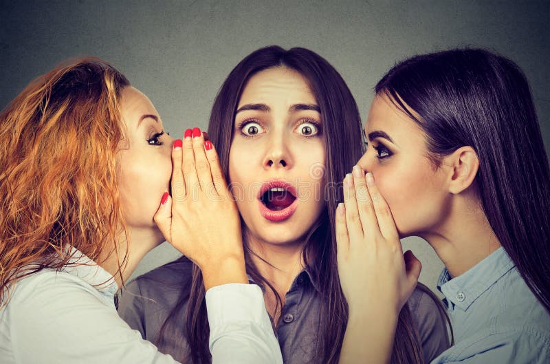 Trois jeunes femmes disant chuchotant un bavardage secret dans l'oreille