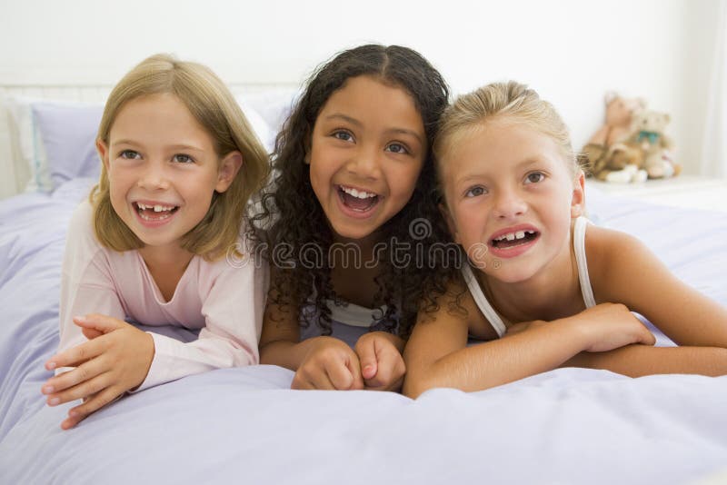 Trois jeunes filles se trouvant sur un bâti dans des leurs pyjamas photo stock Trois jeunes filles se trouvant sur un bâti dans des leurs pyjamas photo stock