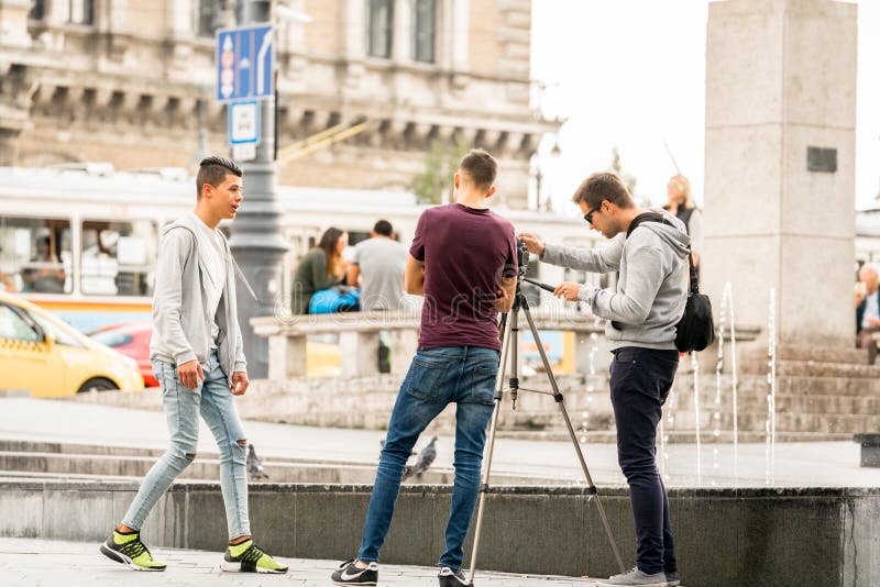 Trois jeunes hommes se filmant à la place de ville à Budapest Hongrie photographie stock Trois jeunes hommes se filmant à la place de ville à Budapest Hongrie photographie stock