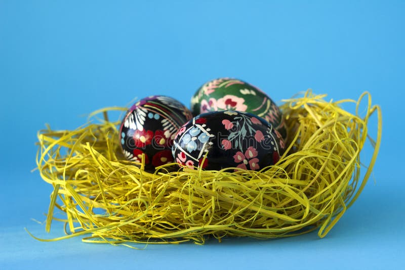 Trois oeufs de pâques décorés se situent dans un nid de foin sur un fond bleu Oeufs de pâques d'Ukrainien avec des ornements et d photographie stock libre de droits Trois oeufs de pâques décorés se situent dans un nid de foin sur un fond bleu Oeufs de pâques d'Ukrainien avec des ornements et d photographie stock libre de droits