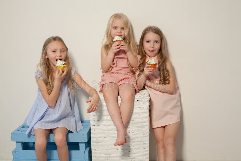 Trois petites filles mangent le gâteau doux avec le petit gâteau crème images libres de droits Trois petites filles mangent le gâteau doux avec le petit gâteau crème images libres de droits