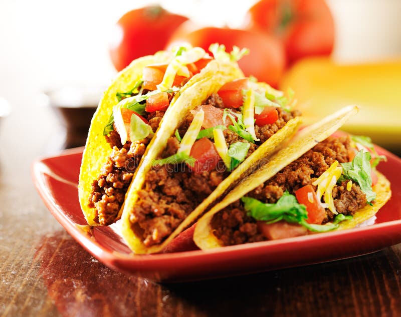 Trois tacos de boeuf avec du fromage, la laitue et des tomates image libre de droits Trois tacos de boeuf avec du fromage, la laitue et des tomates image libre de droits