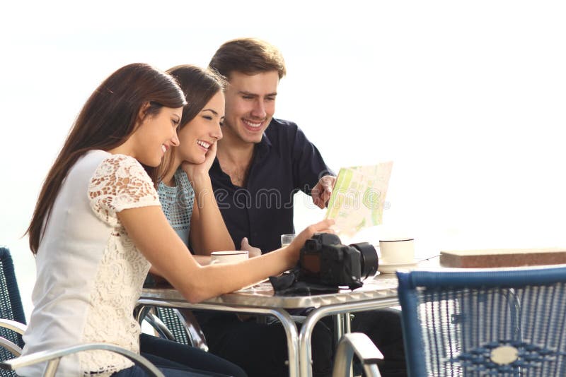 Trois touristes vérifiant le guide dans un café photos stock Trois touristes vérifiant le guide dans un café photos stock