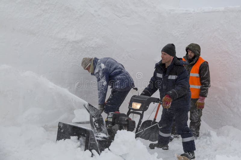 Trois travailleurs dans une tempête de neige pendant le déblaiement de neige photographie stock libre de droits Trois travailleurs dans une tempête de neige pendant le déblaiement de neige photographie stock libre de droits