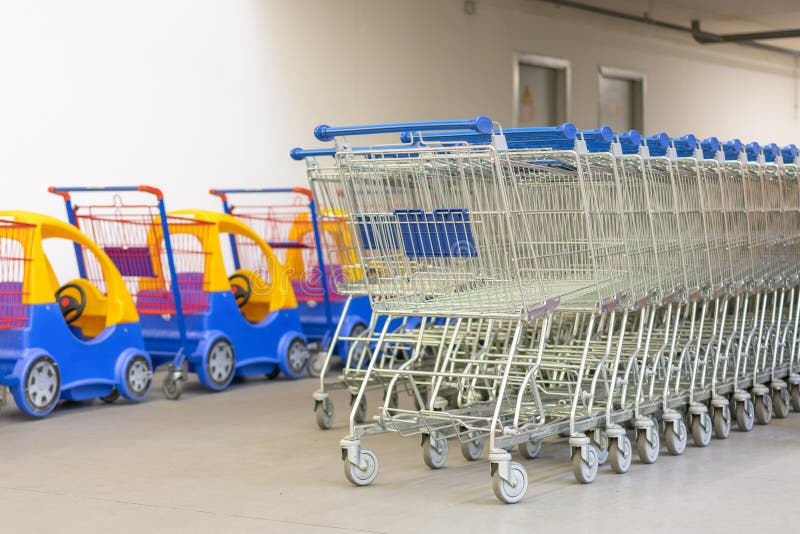 Troles da compra - tema da compra do supermercado Fileira dos carrinhos de compras com punhos do azul e carros das crianças ilustração stock Troles da compra - tema da compra do supermercado Fileira dos carrinhos de compras com punhos do azul e carros das crianças ilustração stock