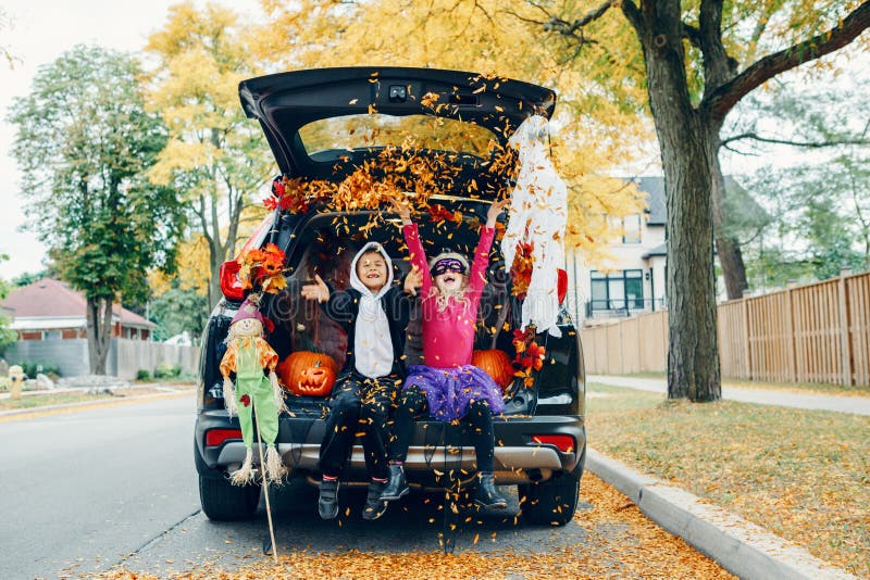 Tronco o tronco Bambini che festeggiano Halloween nel bagagliaio dell'auto Ragazzo e ragazza con zucche rosse festeggiano l'ottob