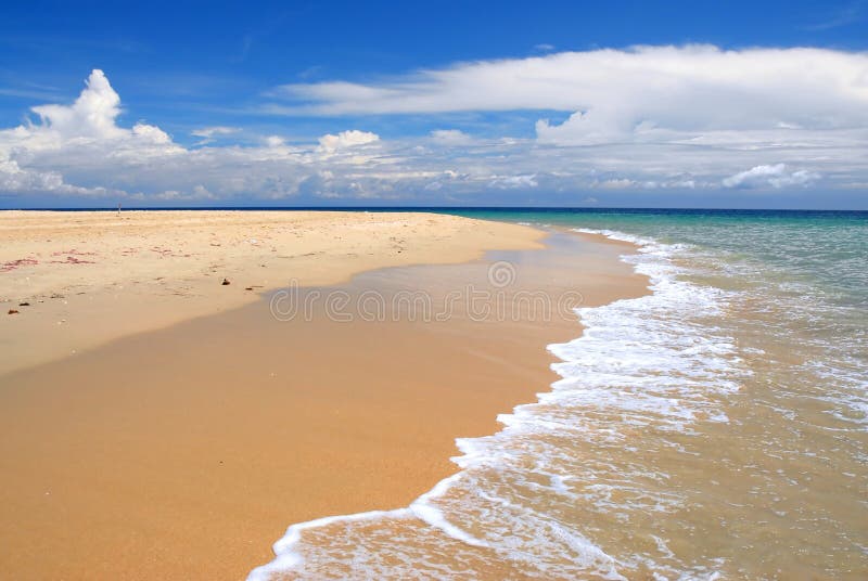 Waves breaking on picturesque beach of tropical island with blue sky and cloudscape background. Waves breaking on picturesque beach of tropical island with blue sky and cloudscape background.
