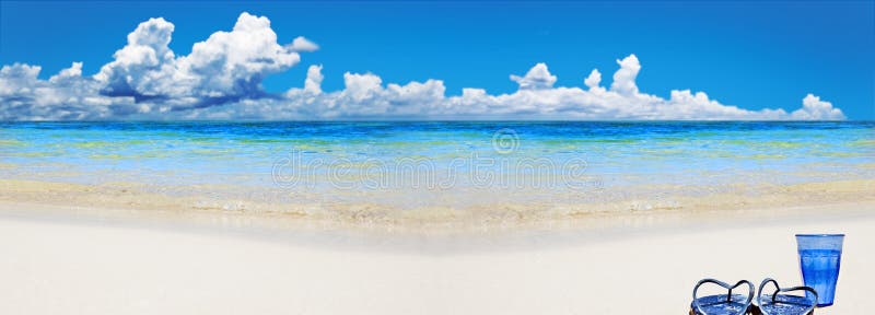 Tropical beach with beach shoes and glass of water