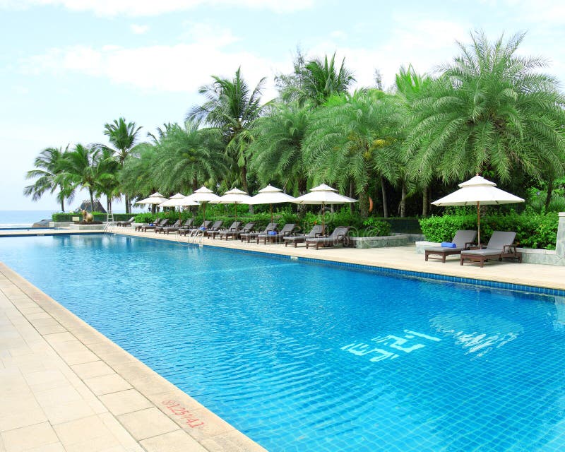 Tropical beach resort hotel swimming pool -- tropical beach vacation and travel concept.