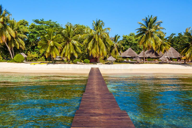 View of the tropical beach from  the wooden pontoon of Sainte-Marie island, East of Madagascar, africa, bathing, boraha, coast, destination, exotic, green, holiday, hot, hotel, hut, idyllic, indian, ocean, jetty, jungle, lagoon, landmark, landscape, lounger, lush, nosy, outdoor, palm, paradise, pier, relax, resort, rest, romantic, sand, scenic, sea, seabed, seascape, spot, straw, summer, sunbed, sunny, touristic, tree, umbrella, vacation. View of the tropical beach from  the wooden pontoon of Sainte-Marie island, East of Madagascar, africa, bathing, boraha, coast, destination, exotic, green, holiday, hot, hotel, hut, idyllic, indian, ocean, jetty, jungle, lagoon, landmark, landscape, lounger, lush, nosy, outdoor, palm, paradise, pier, relax, resort, rest, romantic, sand, scenic, sea, seabed, seascape, spot, straw, summer, sunbed, sunny, touristic, tree, umbrella, vacation