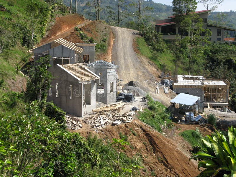 Collina cemento armato casa costruzione sito che appena tagliato pad edificio, ruvida strada di servizio e canale di drenaggio.