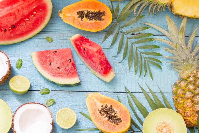 Tropical holiday summer abstract background with palms and fruits on blue planks