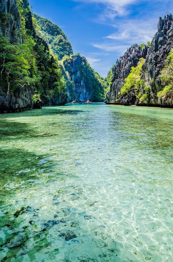Tropical landscape with rock islands, lonely boat and crystal clear water, Palawan, Philippines