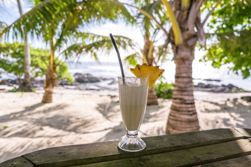 Tropical pina colada cocktail drink with pineapple garnish in glass with straw at exotic beach at Lefaga, Upolu Island, Samoa, So royalty free stock image Tropical pina colada cocktail drink with pineapple garnish in glass with straw at exotic beach at Lefaga, Upolu Island, Samoa, So royalty free stock image