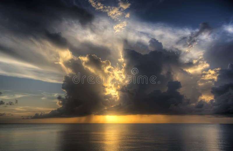 High Dynamic Image of a beautiful sunset setting on the sea covered by clouds. Dynamic colour stock images, royalty-free photos and pictures