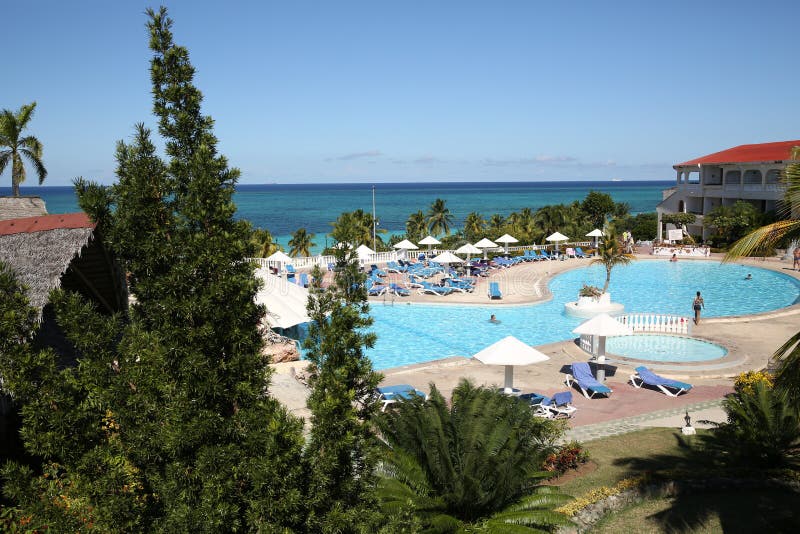 View with palm trees and umbrella of a tropical beach and pool in the Caribean. View with palm trees and umbrella of a tropical beach and pool in the Caribean