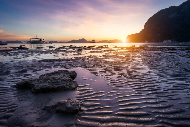 Tropischer Strand in der Ebbezeitebbe auf Sonnenuntergang Mudflats und Sonnenreflexionen an der goldenen Stunde Gebirgsketteninse stockbild Tropischer Strand in der Ebbezeitebbe auf Sonnenuntergang Mudflats und Sonnenreflexionen an der goldenen Stunde Gebirgsketteninse stockbild
