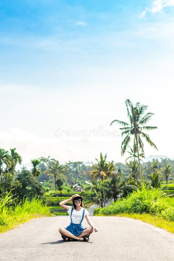 Tropisches Porträt der jungen glücklichen Frau mit Strohhut auf einer Straße mit Kokosnusspalmen und tropischen Bäumen Bali-Insel lizenzfreies stockfoto Tropisches Porträt der jungen glücklichen Frau mit Strohhut auf einer Straße mit Kokosnusspalmen und tropischen Bäumen Bali-Insel lizenzfreies stockfoto