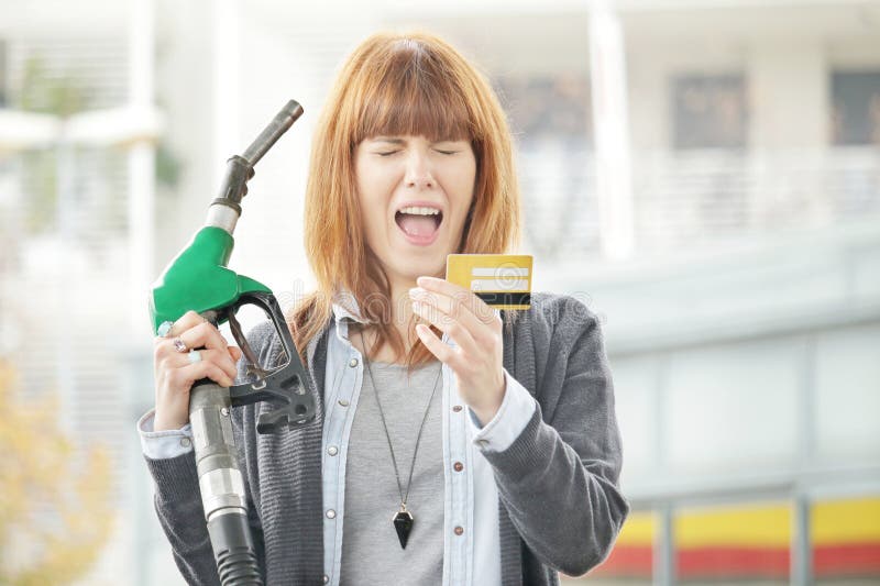 Pretty young lady shocked by high fuel price or the credit card scam at the petrol pump. Pretty young lady shocked by high fuel price or the credit card scam at the petrol pump