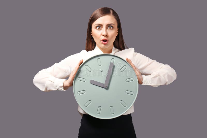 Troubled woman with clock on grey background. Time management concept stock image Troubled woman with clock on grey background. Time management concept stock image
