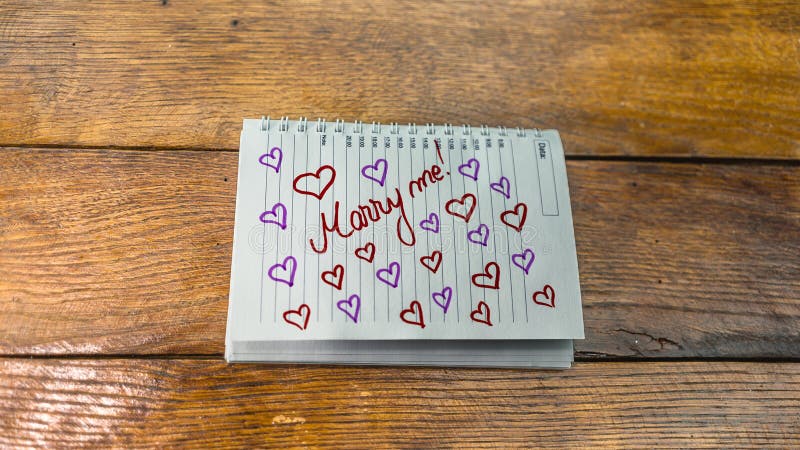 Marry me, writing love text on paper, lovely message. Text on spiral agenda. Romantic, love concept. Valentine`s day. Marry me, writing love text on paper, lovely message. Text on spiral agenda. Romantic, love concept. Valentine`s day