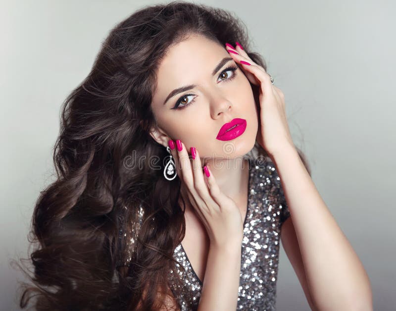 Makeup. Beautiful girl portrait. Long hair. Brunette fashion woman with red lips, manicured nails, healthy curly shiny hairstyle posing on studio background. Makeup. Beautiful girl portrait. Long hair. Brunette fashion woman with red lips, manicured nails, healthy curly shiny hairstyle posing on studio background.