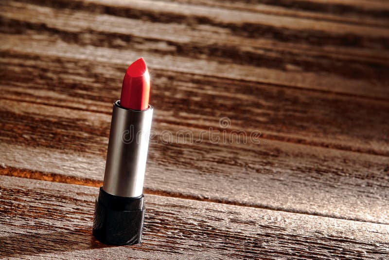 Trucco rosso del tubo del rossetto su superficie di legno approssimativa fotografie stock Trucco rosso del tubo del rossetto su superficie di legno approssimativa fotografie stock